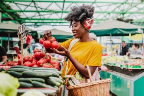 POC妇女拿着菜篮在露天菜市场买西红柿