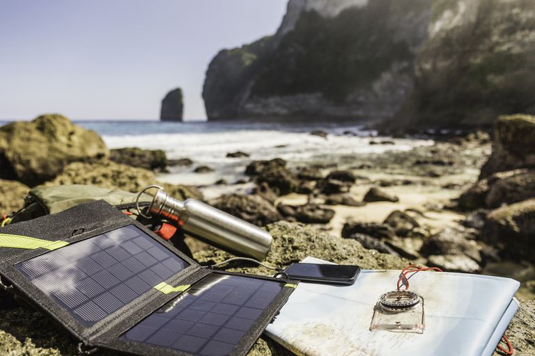 在海边为笔记本电脑充电的便携式太阳能电池板。＂class=