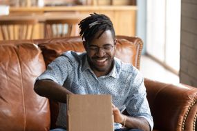 Smiling man opening a gift in a cardboard box