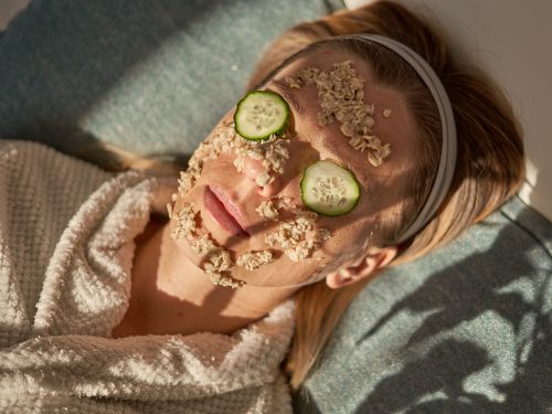 金发女子放松与黄瓜眼罩和diy燕麦磨砂在脸上