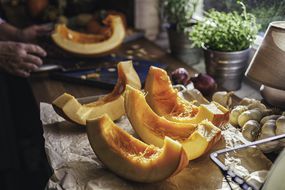 将新鲜的南瓜切成质朴的厨房中的切片。