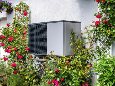 玫瑰环绕的房子上热泵供暖的室外机