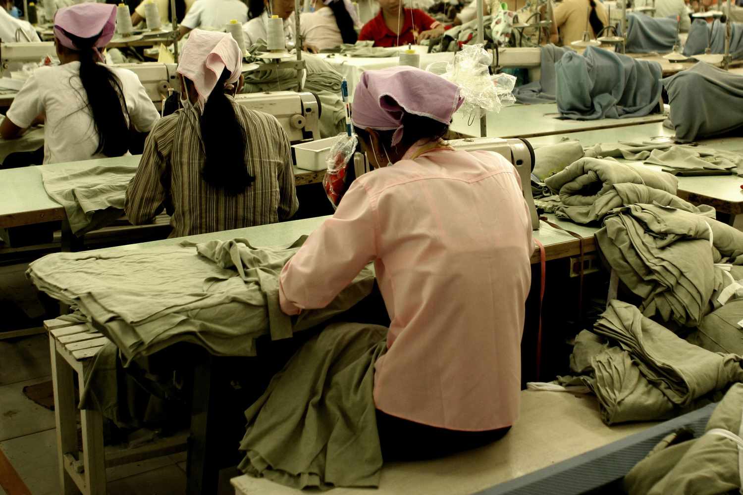 在一家服装厂工人坐在缝纫机在东南亚