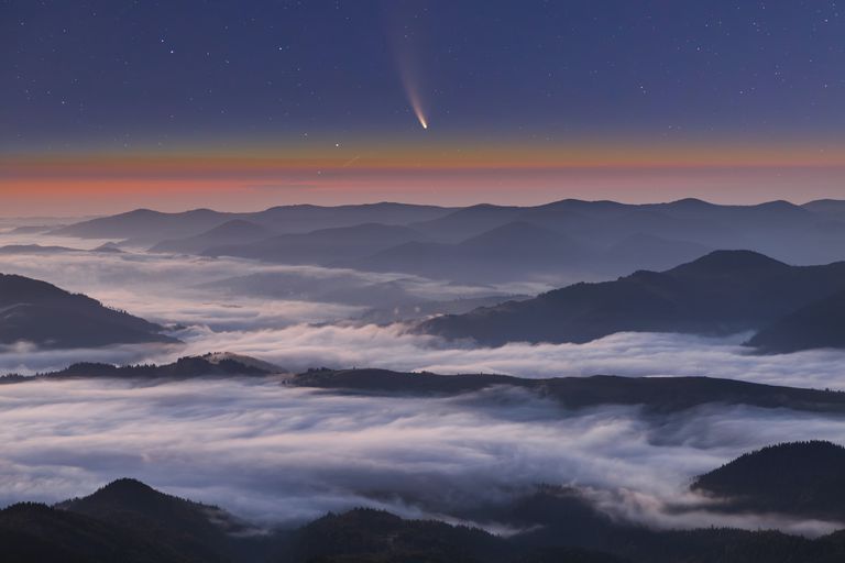 彗星Neowise C/2020 F3在雾蒙蒙的山脉上日落”class=