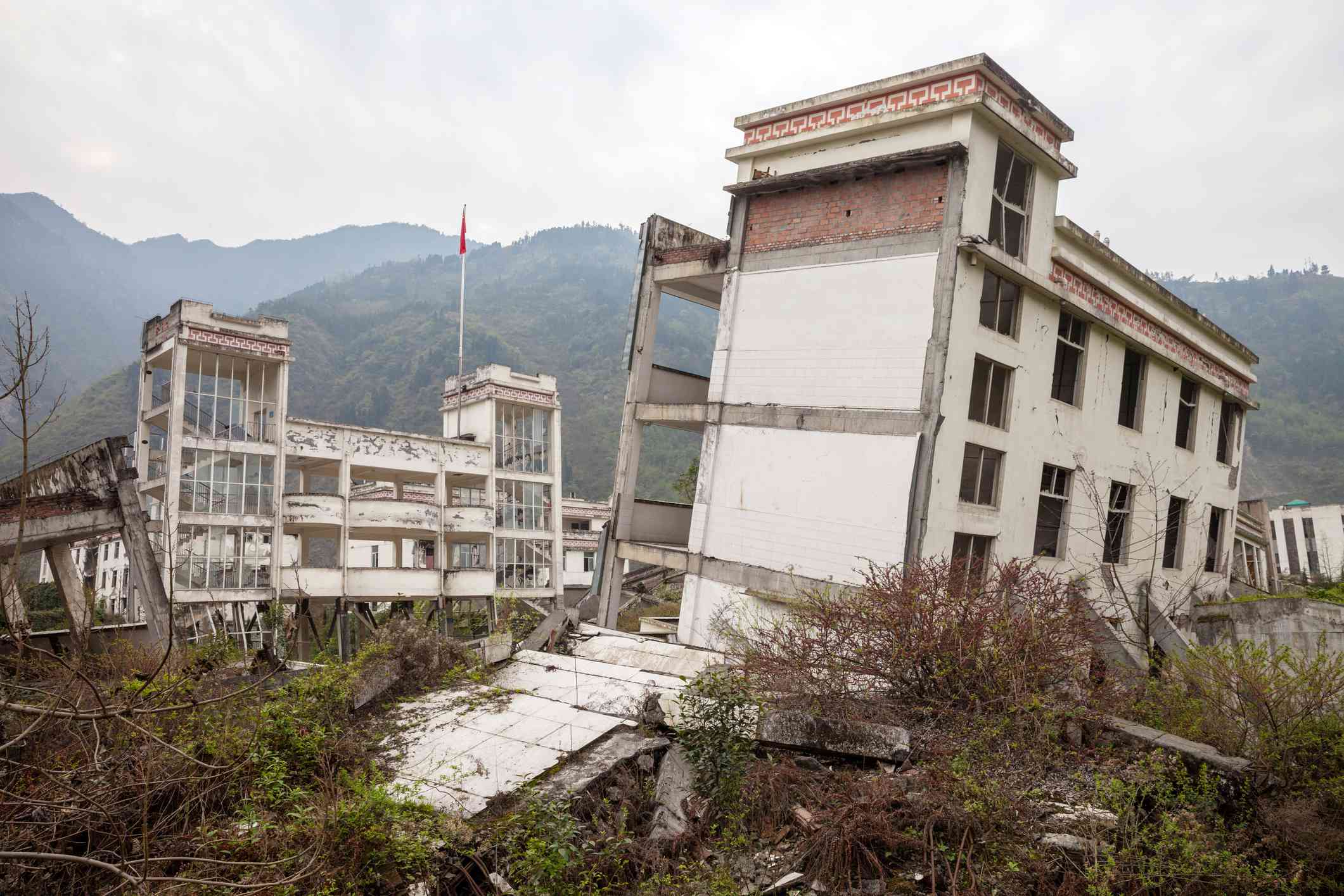 以山为背景的地震损坏的建筑物＂width=