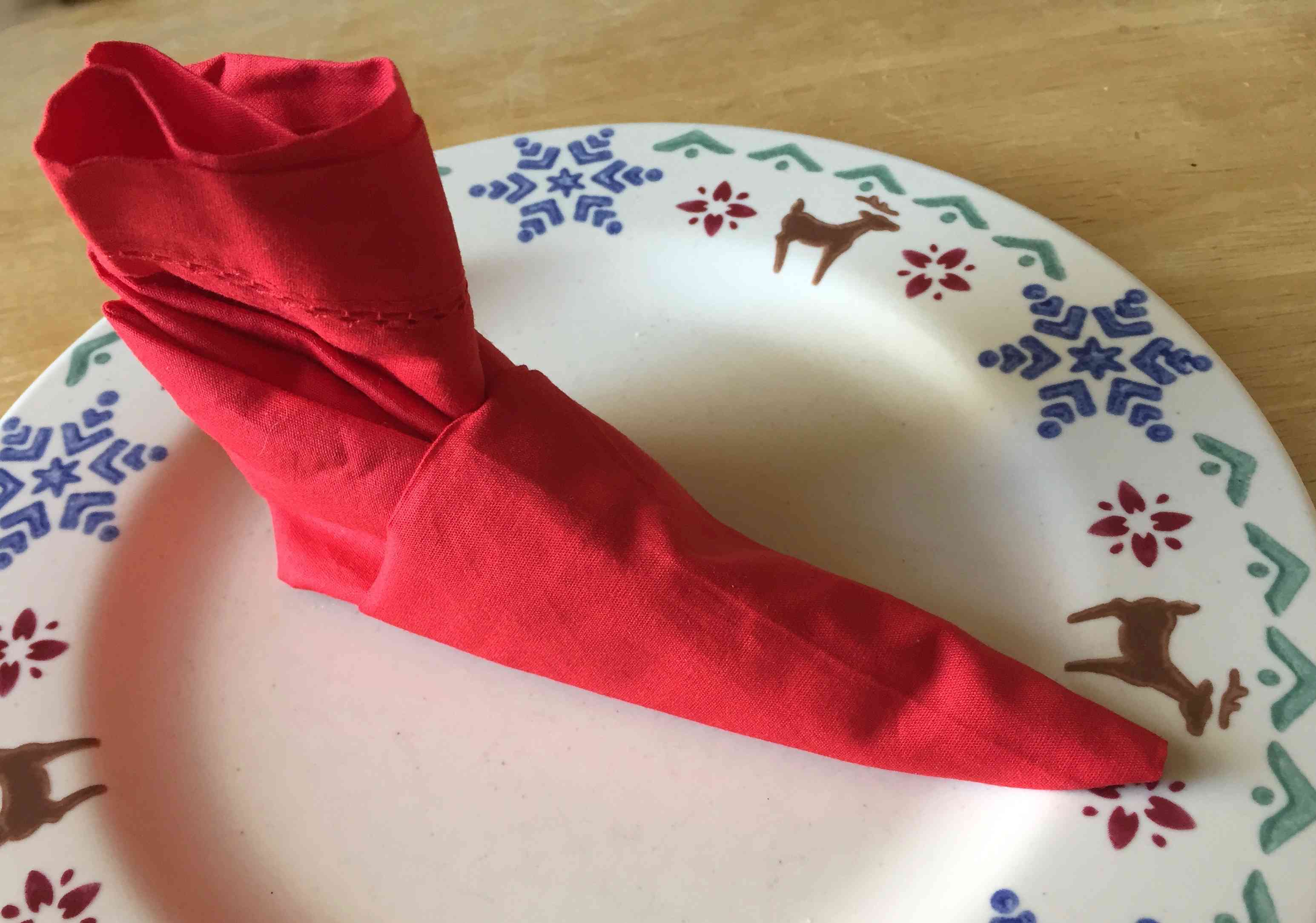 红色的餐巾折叠成驯鹿板上的小精灵靴子形状