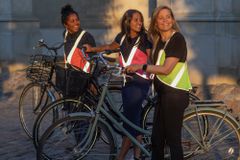 三个女人穿着反光的维斯珀廷生态背心和自行车