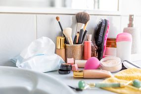Messy cosmetics and beauty tools on a bathroom counter