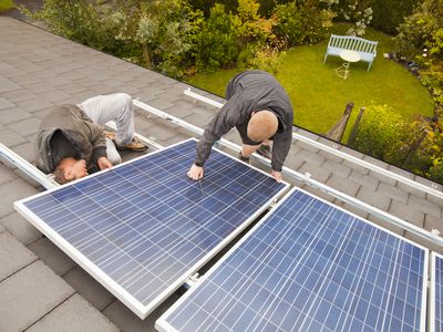 技术人员安装太阳能照片伏打板在Ambleside房子屋顶,英国坎布里亚郡。