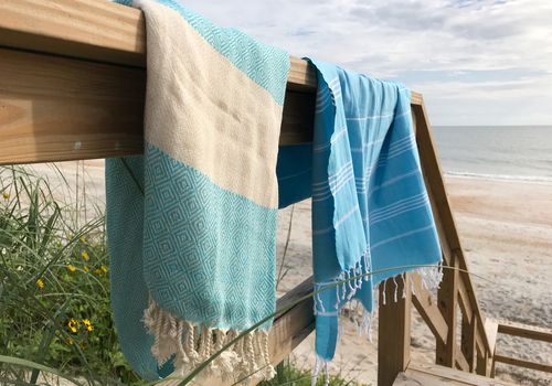 2条土耳其毛巾挂在海滩的栏杆上