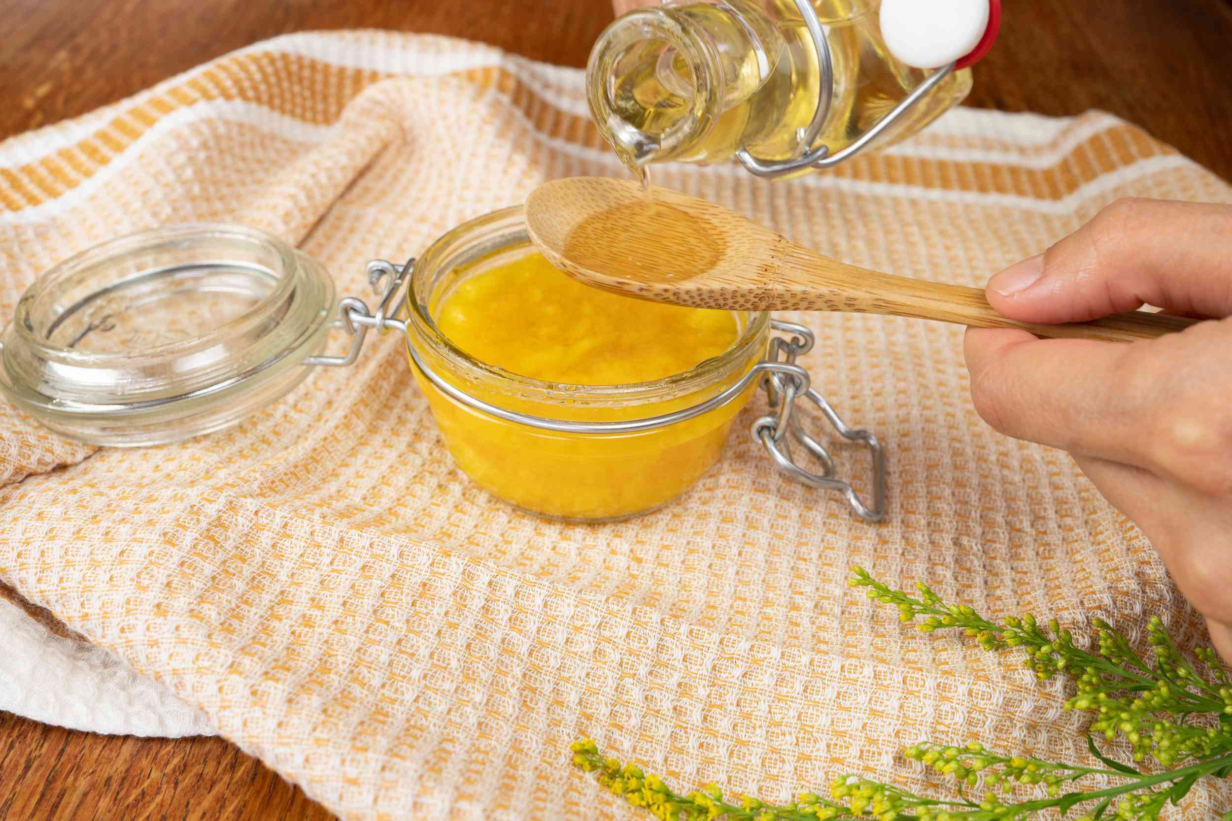 将蜂蜜倒入木勺中，在玻璃罐中制作自制的芒果面罩