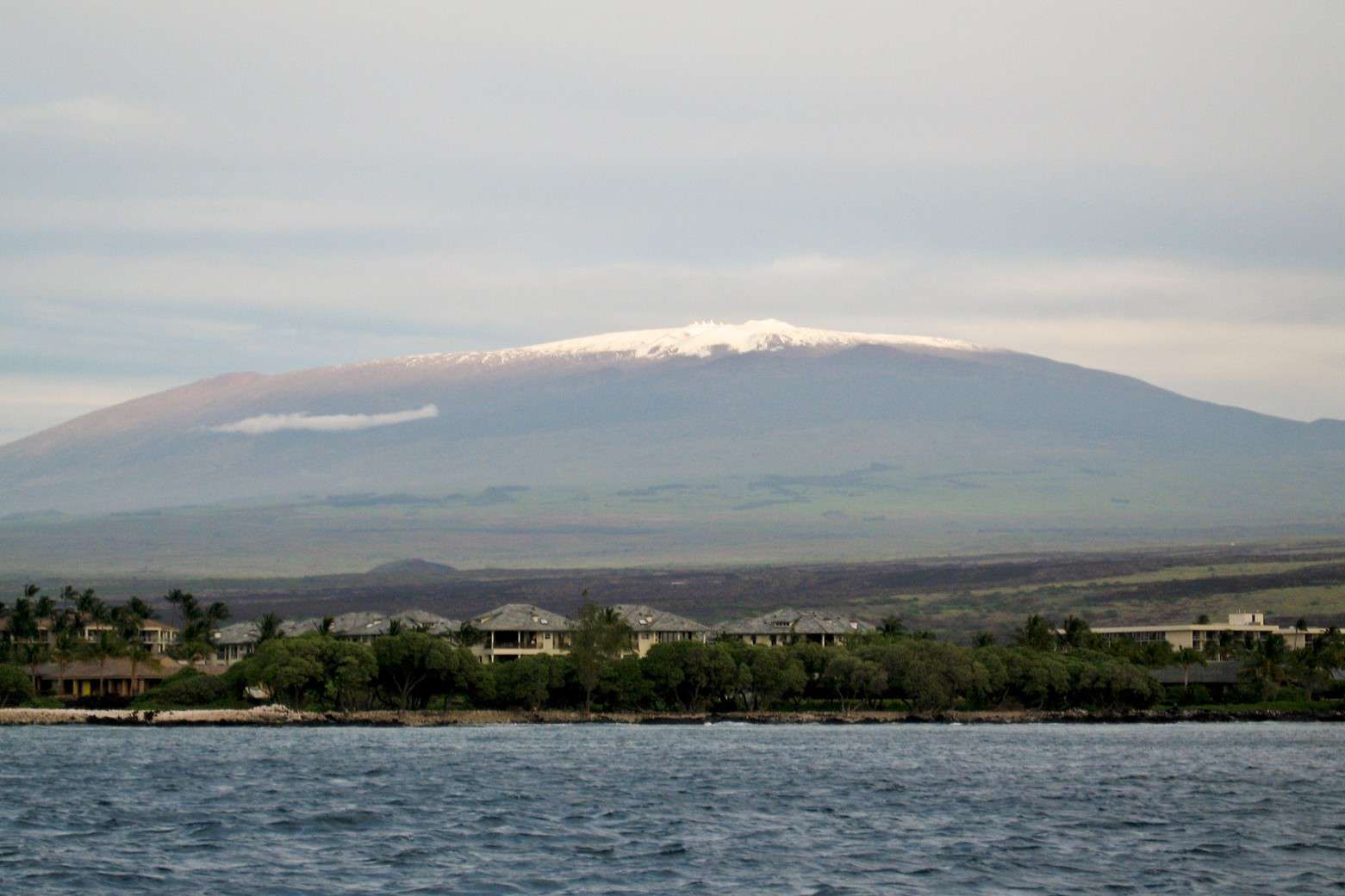 夏威夷的莫纳克亚山远处有雾和海滨小镇＂width=