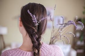 黑发女子与辫子的头发有新鲜的薰衣草枝塞进辫子和花束