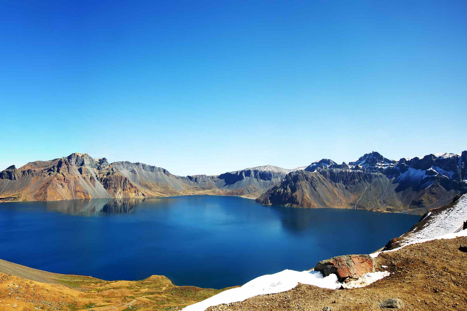 深蓝色的火山口湖被不规则的褐色小山包围的全景