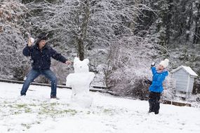 父亲和孩子在积雪的后院打雪仗