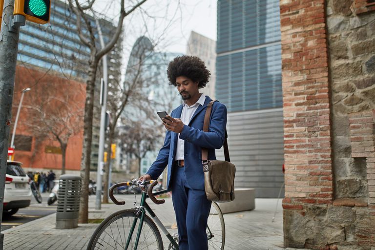 一位商人站在人行道上的自行车旁看手机