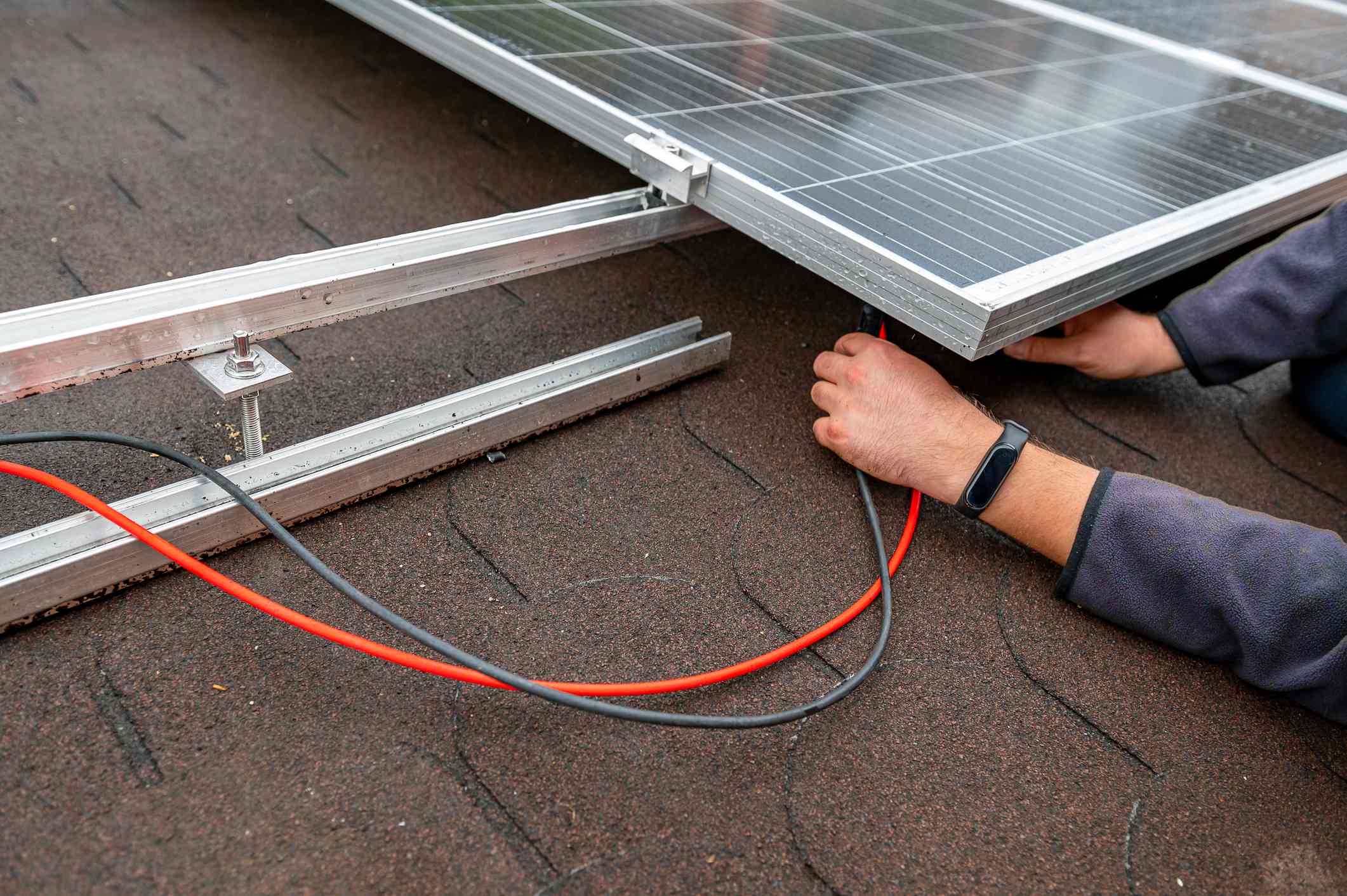 男子在屋顶安装太阳能电池板＂width=