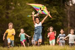 一大群快乐的孩子在春天带着风筝奔跑。
