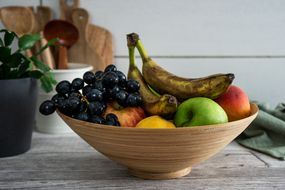 碗旧果子和被擦伤的香蕉吸引果子在厨房柜台上飞行“width=