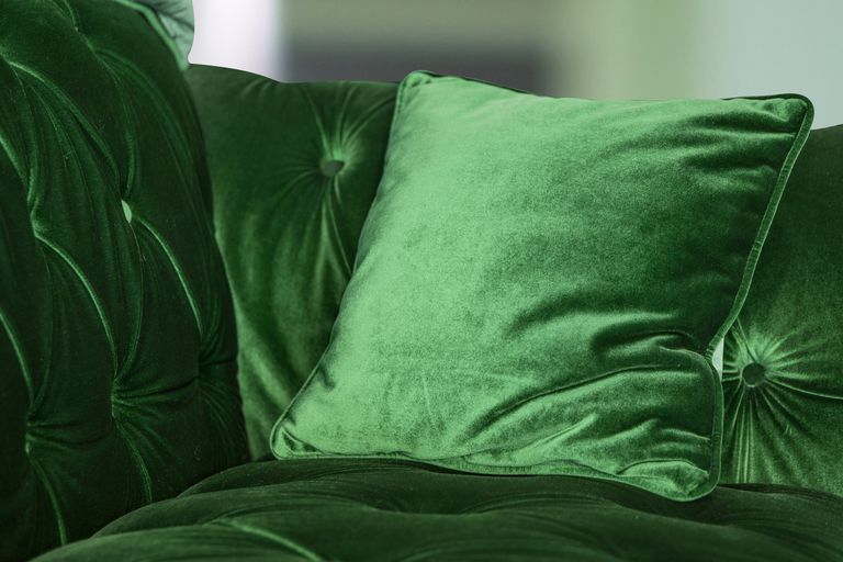 家里的绿色丝绒沙发带靠垫＂class=