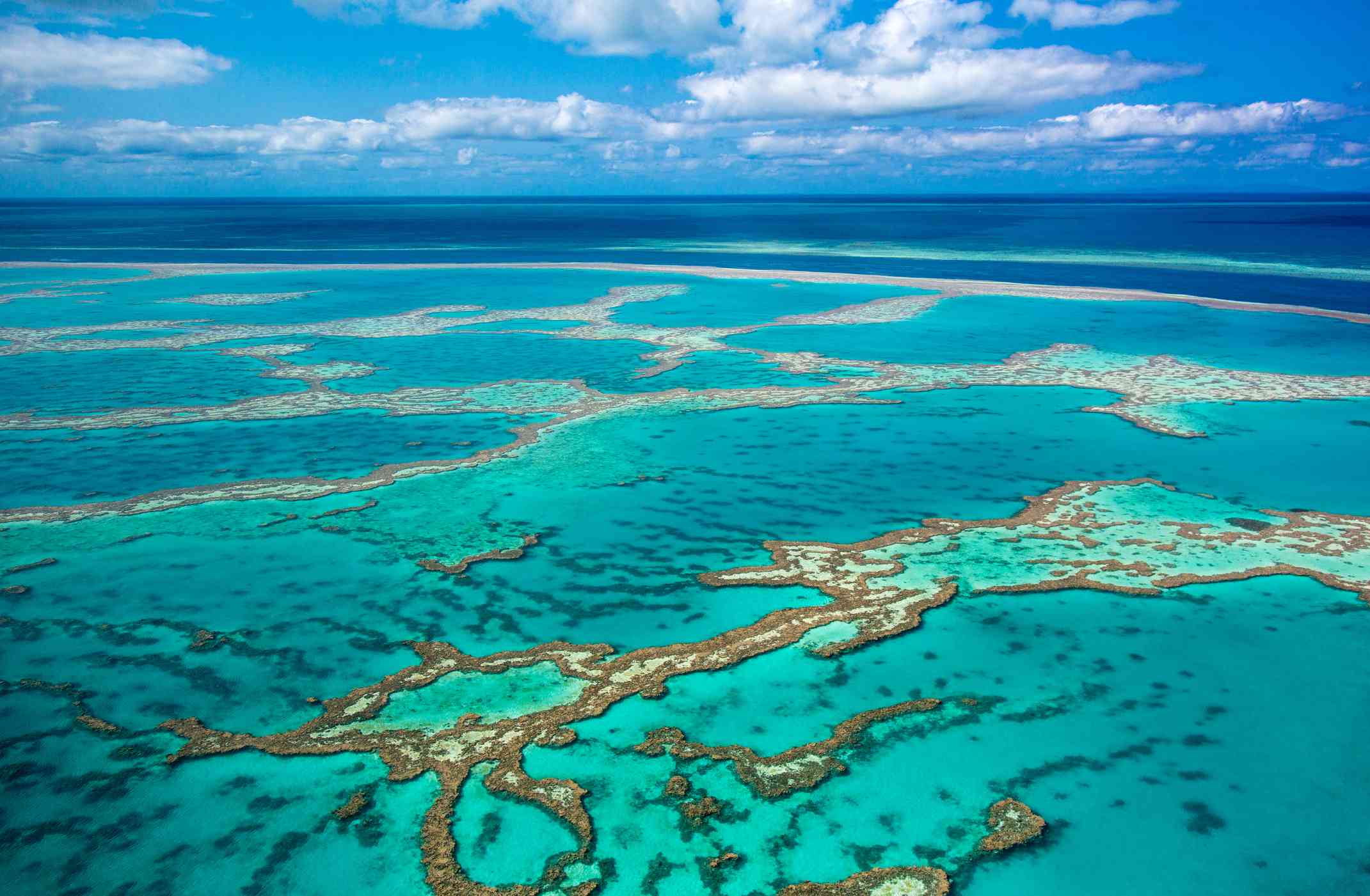 航拍的大堡礁显示珊瑚礁地区蓝绿色的水和略多云的天空背景