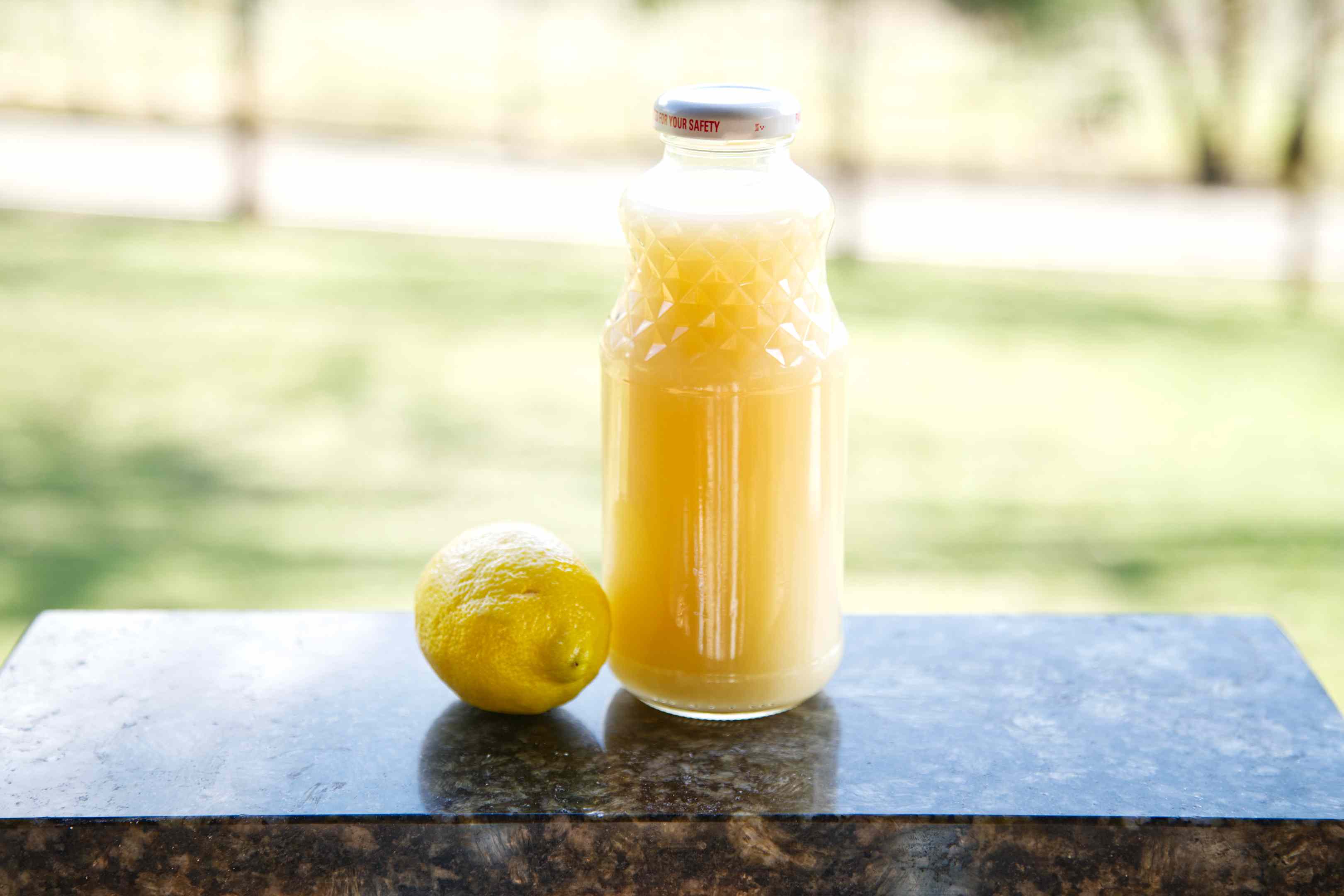 玻璃瓶柠檬汁，旁边是整个柠檬，放在大理石砧板上