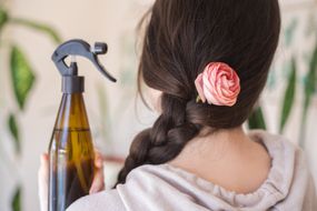 女人的背部露出长长的辫子，粉红色的玫瑰和自制的棕色瓶发胶