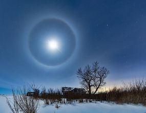 A lunar halo shines above a farm house in winter.