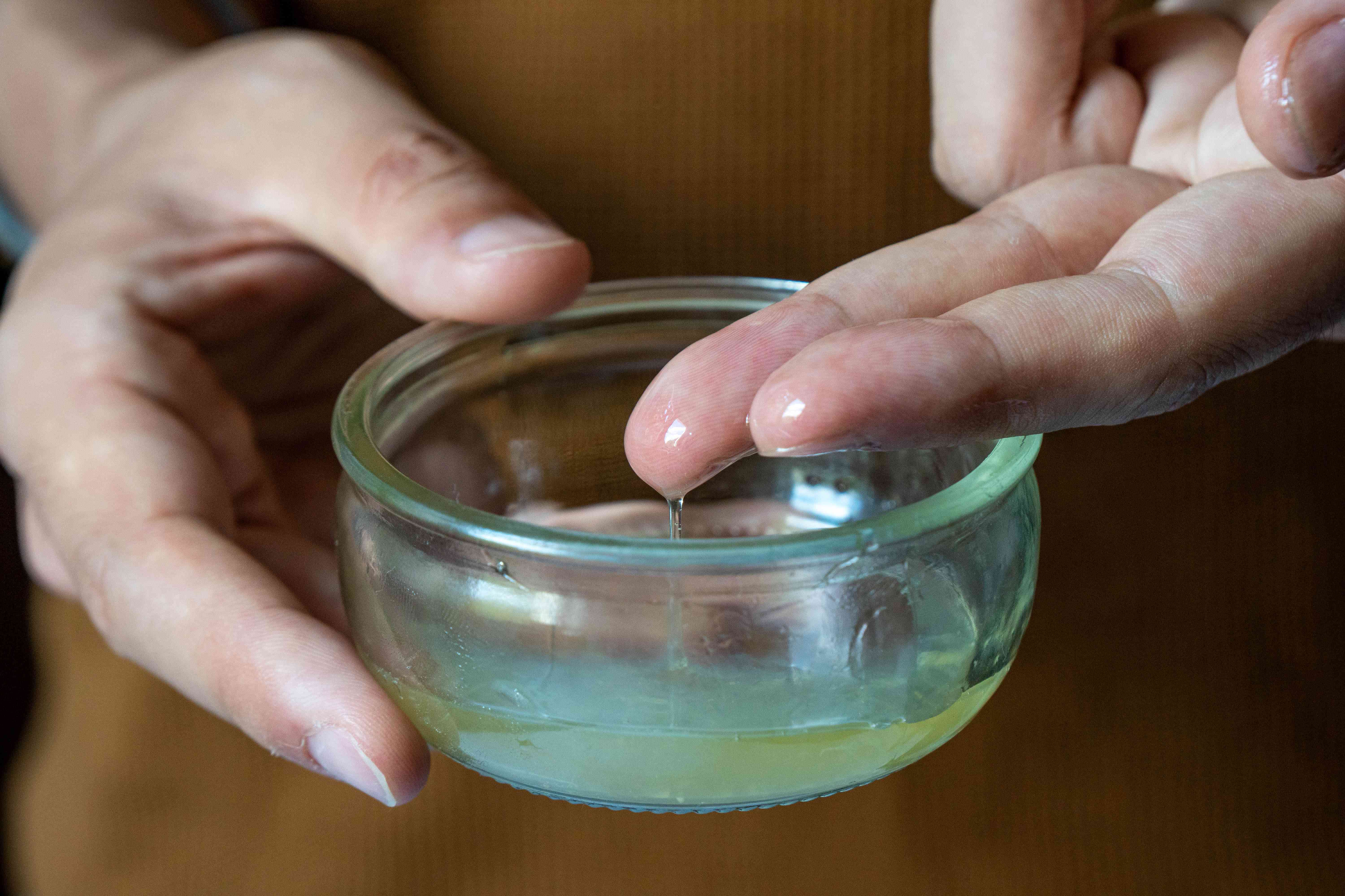 近距离的手浸手指芦荟维拉柠檬蜂蜜面膜在玻璃碗