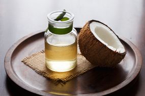 椰子油与木制背景上的新鲜椰子一半