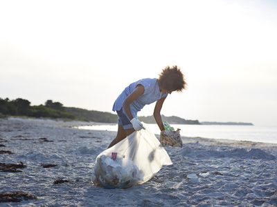 人从海滩上收集垃圾,并把它在袋子里