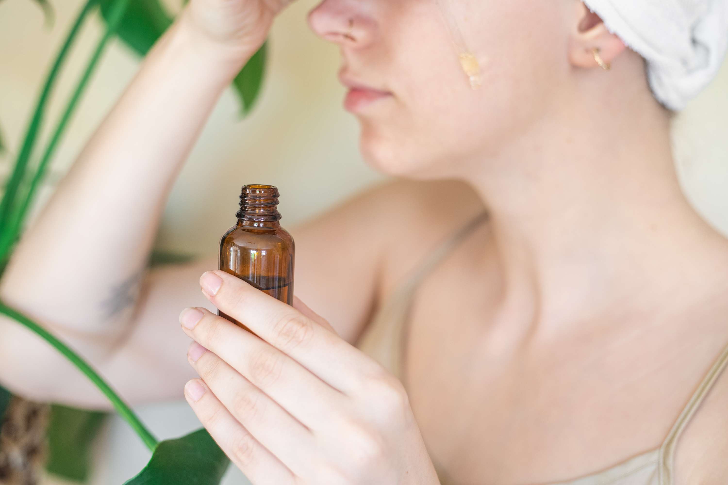 头发包裹中的女人从玻璃棕色瓶中涂上直摩变的油，脸部脸部清洁剂