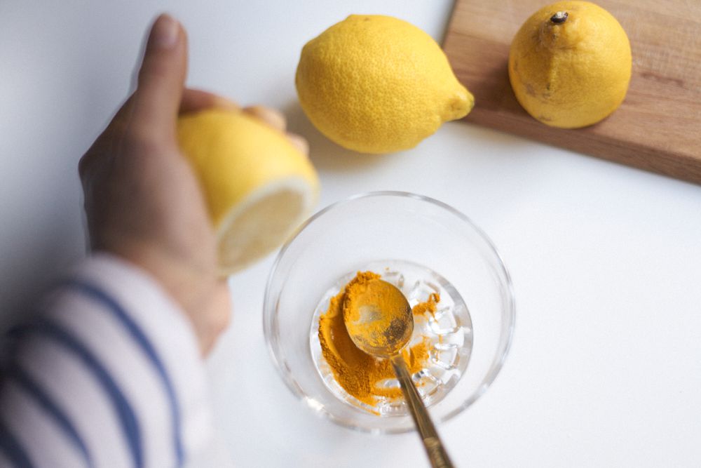 手动将柠檬挤入玻璃碗中，用姜黄粉和冰作为黑眼圈“width=