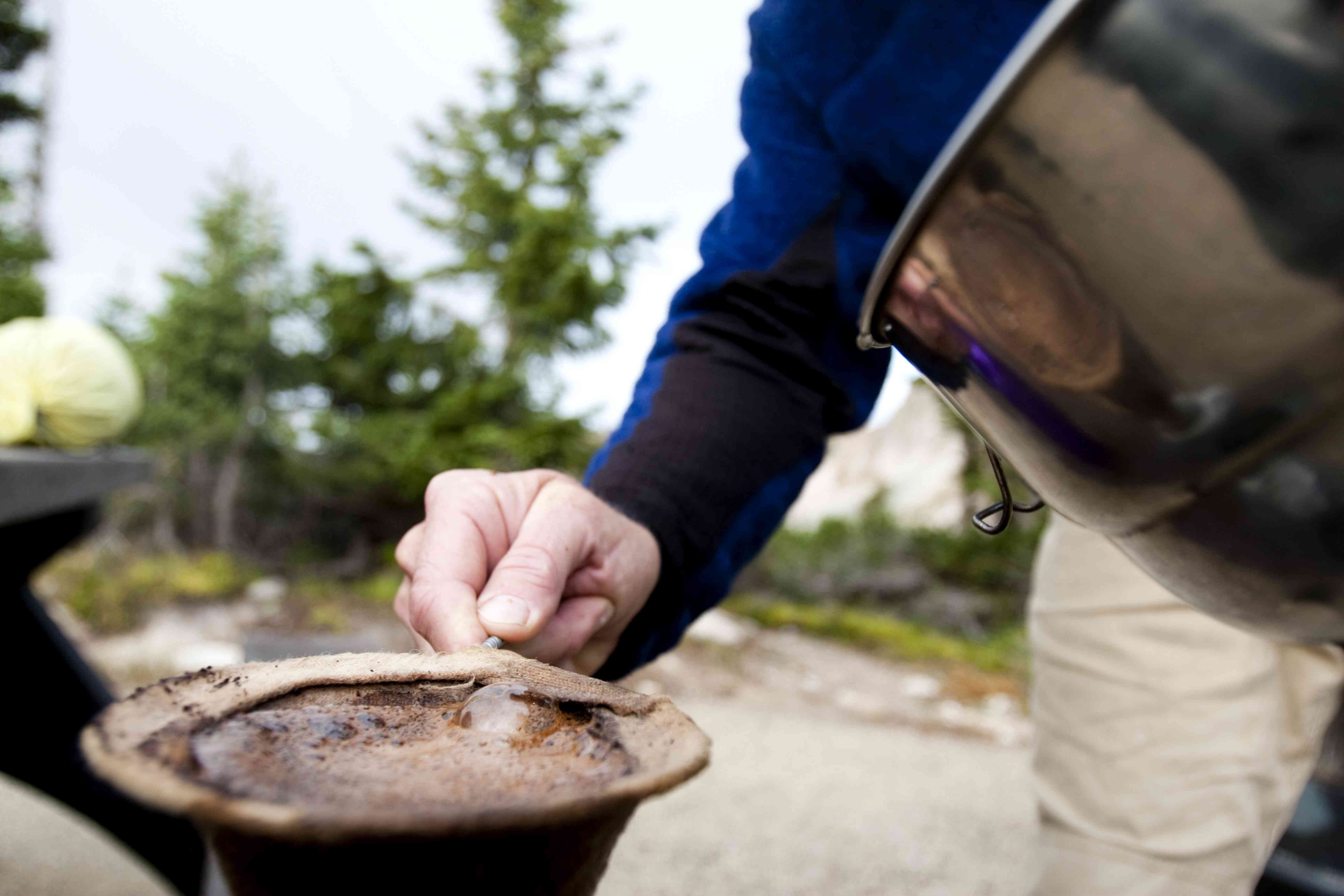 一个男人在怀俄明州的下雪山脉的露营地煮早晨咖啡。