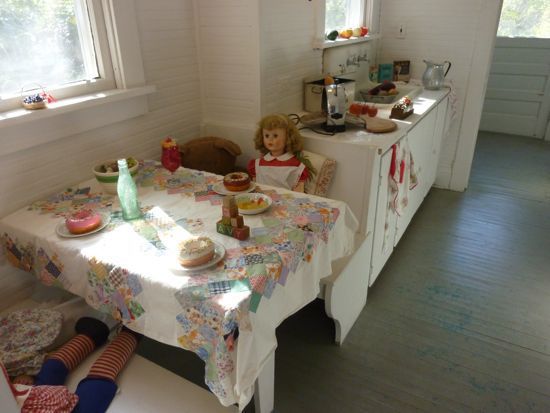 一间老式厨房，桌上放着玩偶。