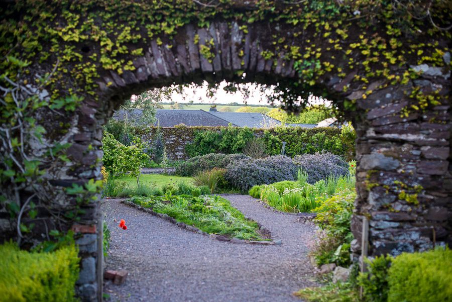 透过爬满常春藤的石拱，可以看到一座花园
