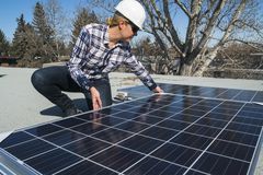 女建筑工人正在住宅屋顶上安装太阳能电池板。