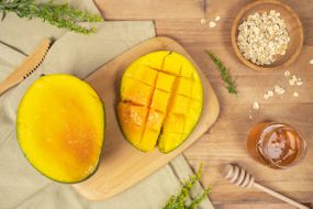 芒果在切菜板上用蜂蜜和燕麦切成一半，用于DIY面罩