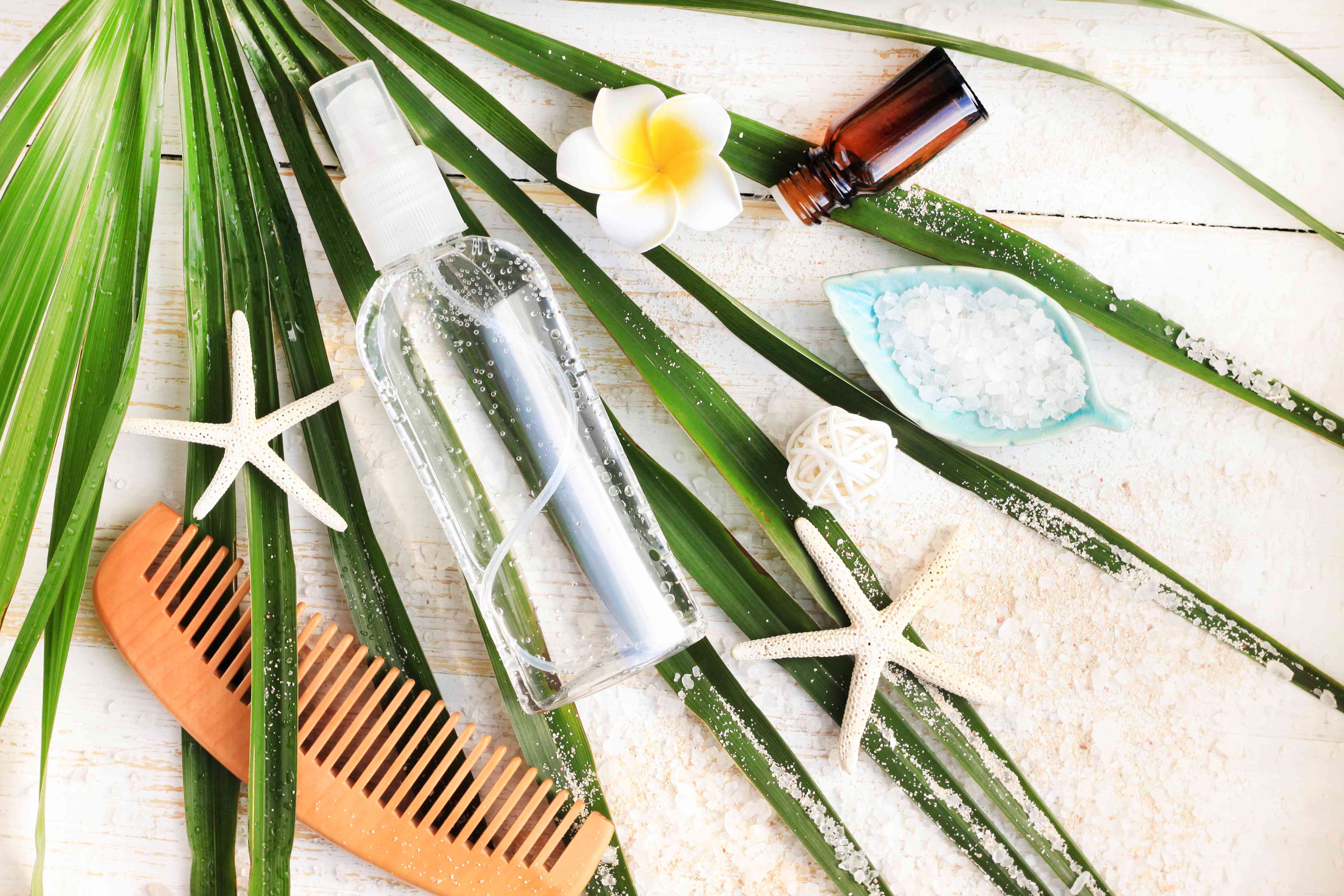 夏季美容护理套件。一瓶矿物海盐头发和身体喷雾，从上方观察到绿色棕榈叶