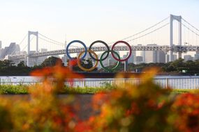 2021年8月4日，日本东京台场海洋公园，2020年东京奥运会第12天日落时，奥运五环装置和彩虹桥的总览。