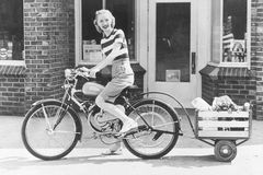 一个女人骑着货物拖车骑自行车的老式照片。