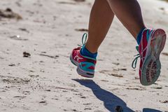 穿着蓝色和粉色运动鞋在沙滩上跑步的人