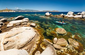 在撒丁岛南海岸被岩石包围的清澈水域中，一对皮划艇手