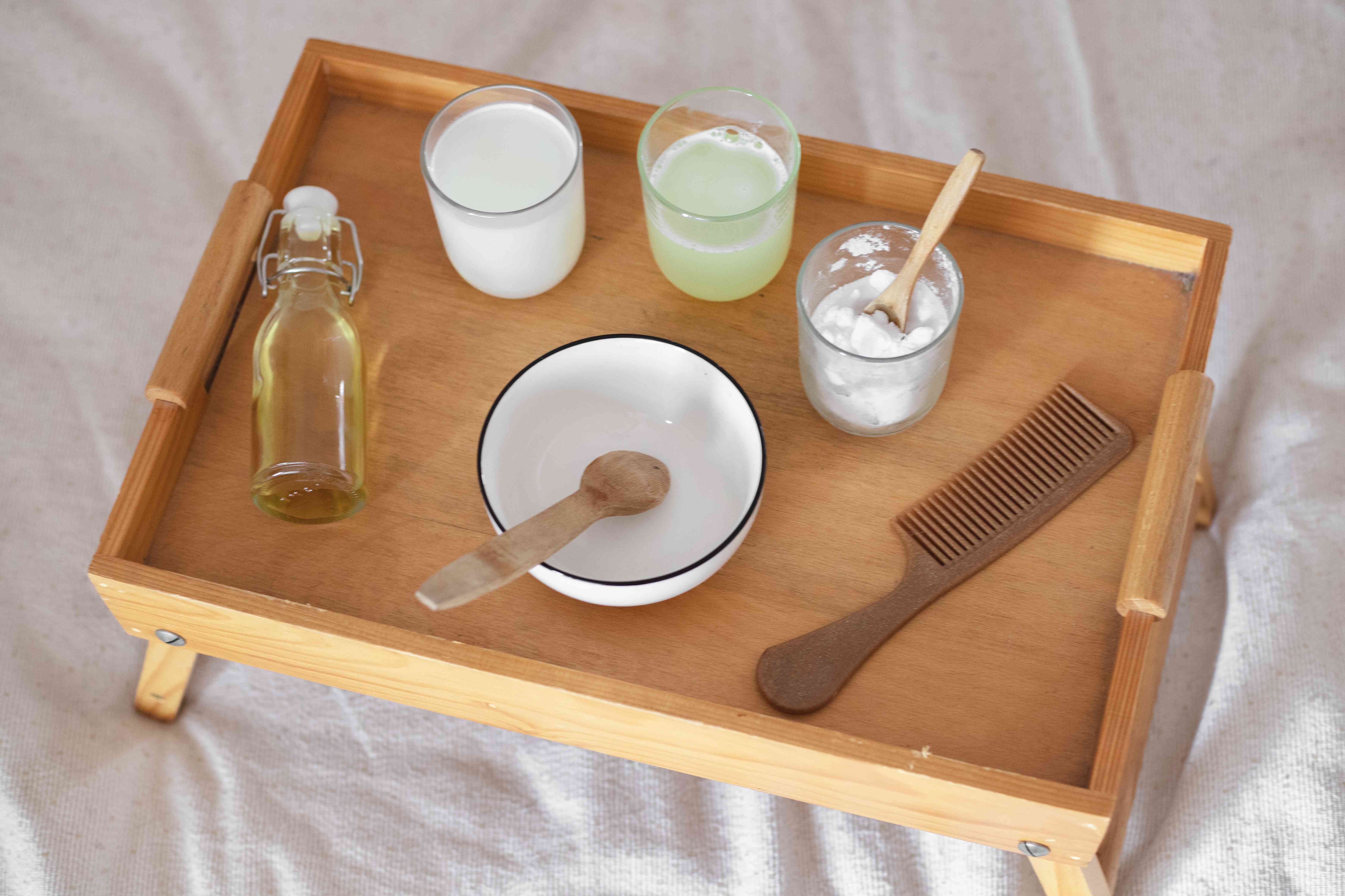 木制早餐托盘，白色床上，各种DIY天然发膜成分和梳子