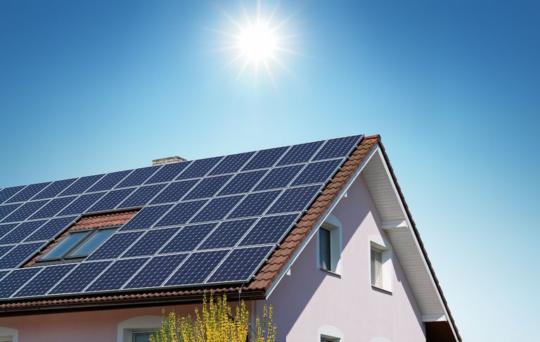 太阳照耀房屋的屋顶上覆盖着太阳能电池板。”class=