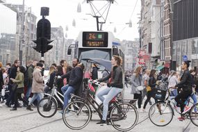 在阿姆斯特丹，人们步行、骑自行车和乘坐交通工具＂width=