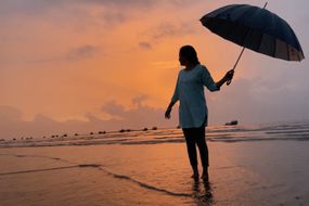 孟买，一名女子打着伞站在海滩上