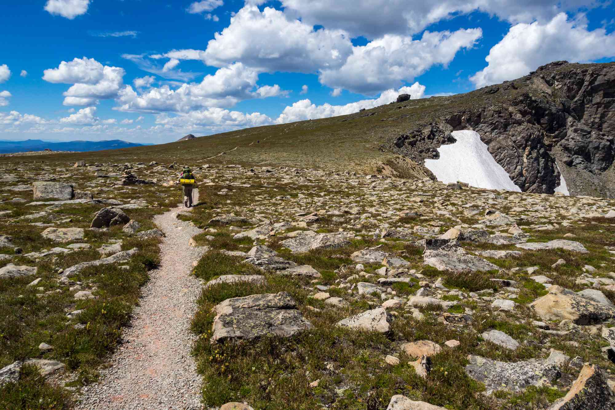 孤独的在山上徒步旅行者峰会草甸在落基山脉”width=