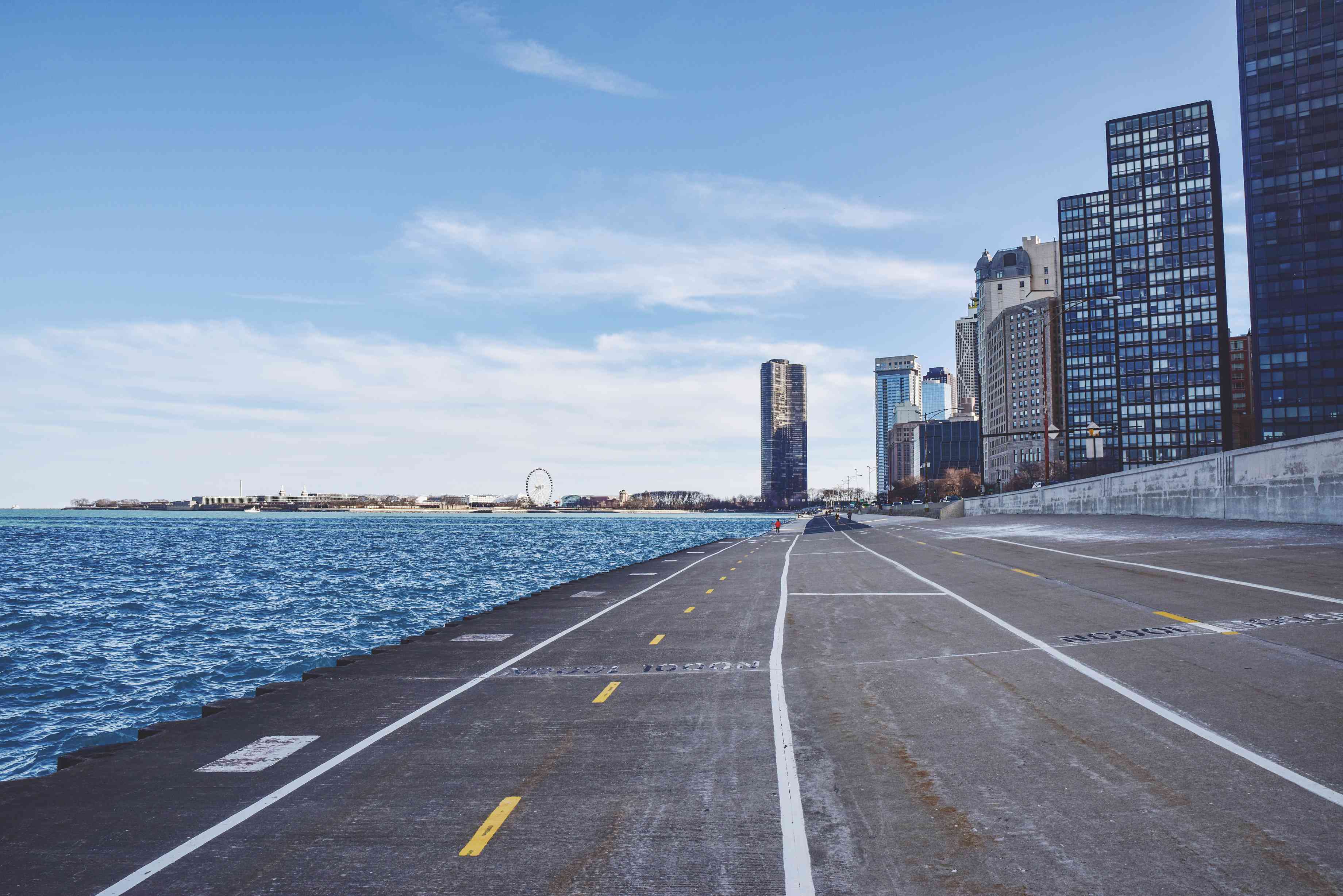 在芝加哥的天际线前，有一条宽阔的混凝土自行车道，上面画着线条