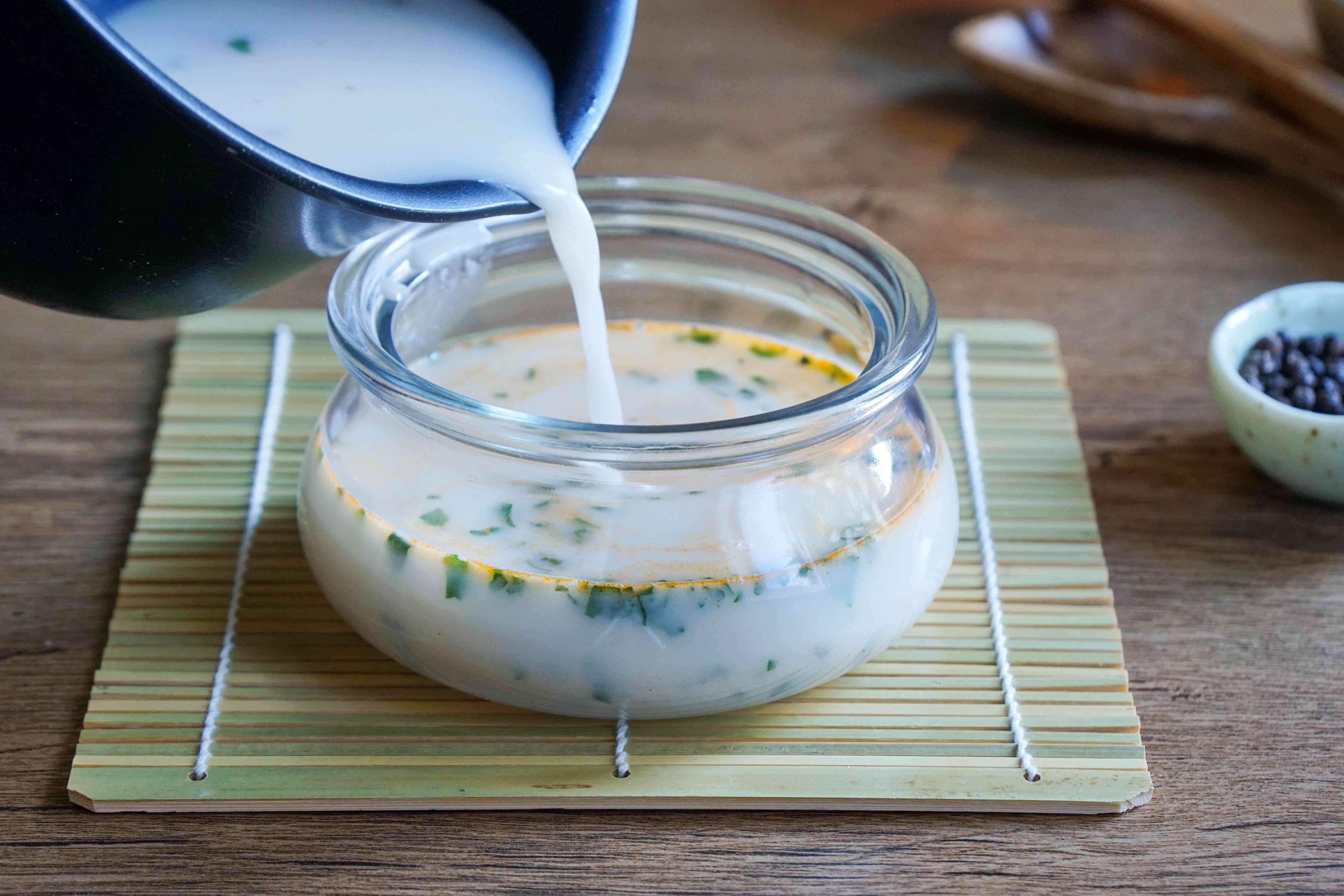 乳汤从平底锅倒入玻璃罐中，放在竹席上